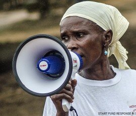 ActionAid volunteer facilitator Hawa Jalloh conducts an Ebola awareness session with an ActionAid loudspeaker in the village of Mbundorbo, near Bo.